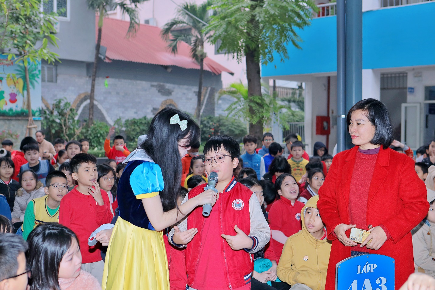A person speaking into a microphone to a group of children

Description automatically generated
