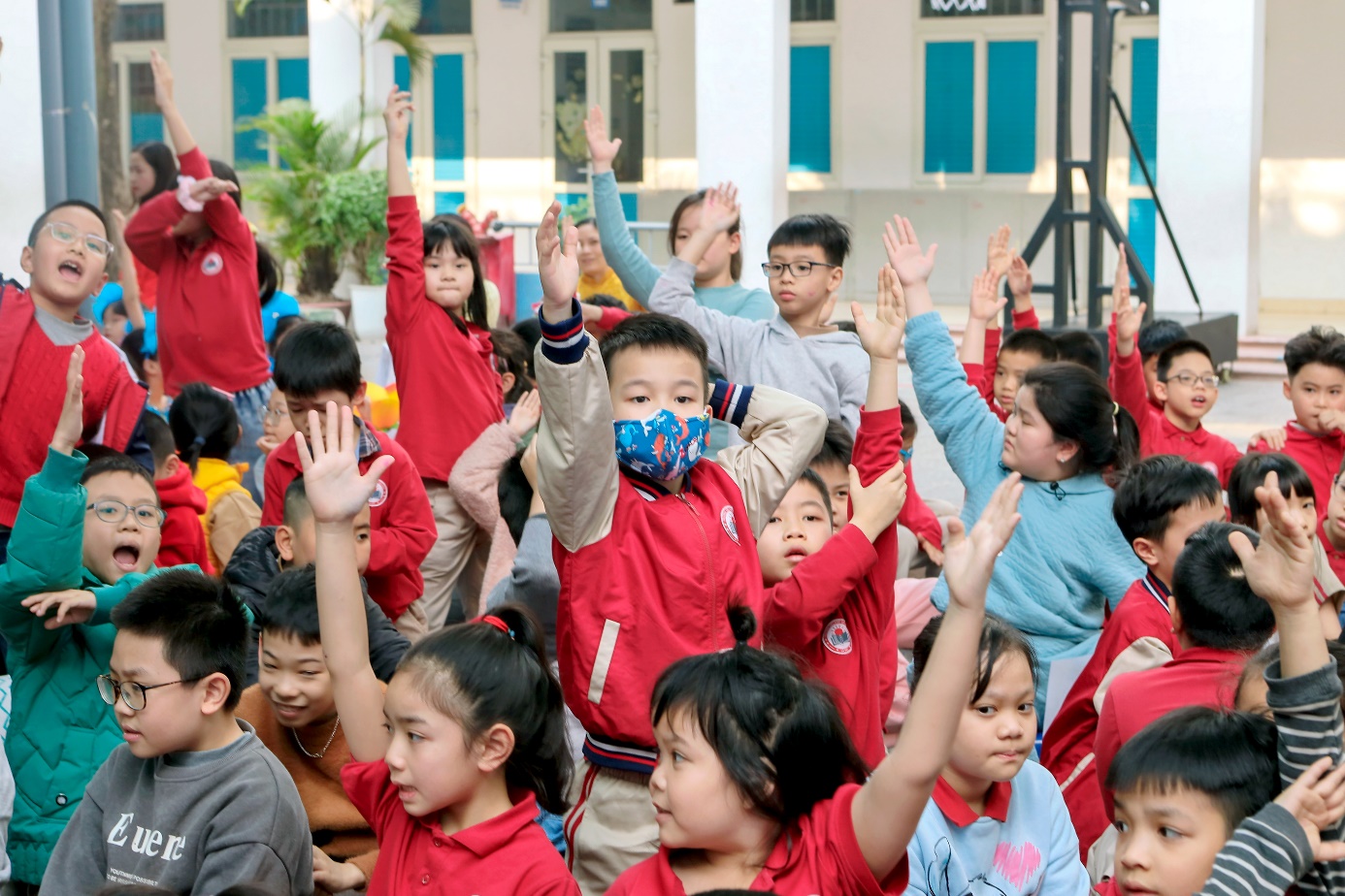 A group of children raising their hands

Description automatically generated