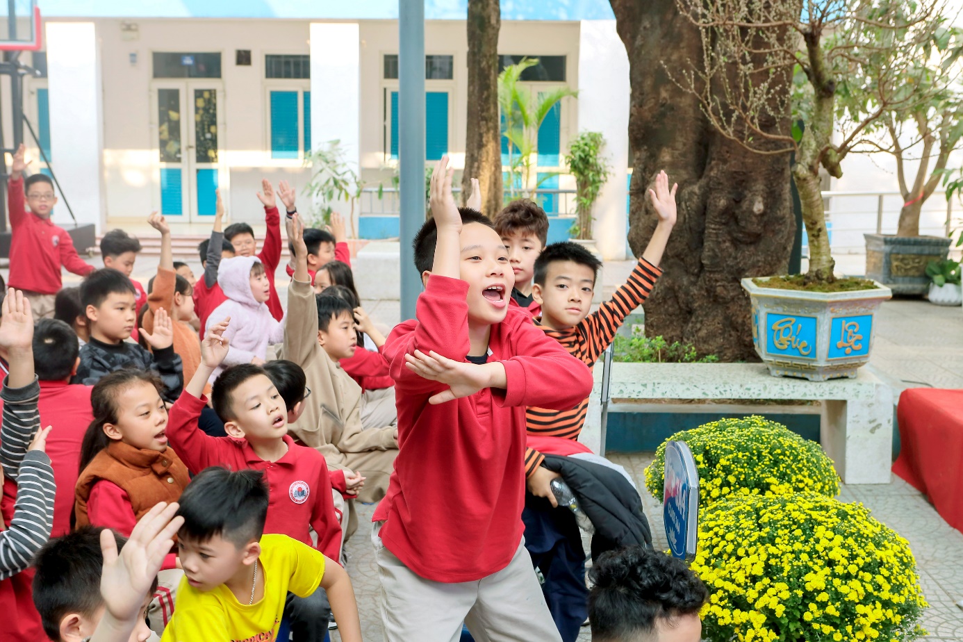 A group of children raising their hands

Description automatically generated
