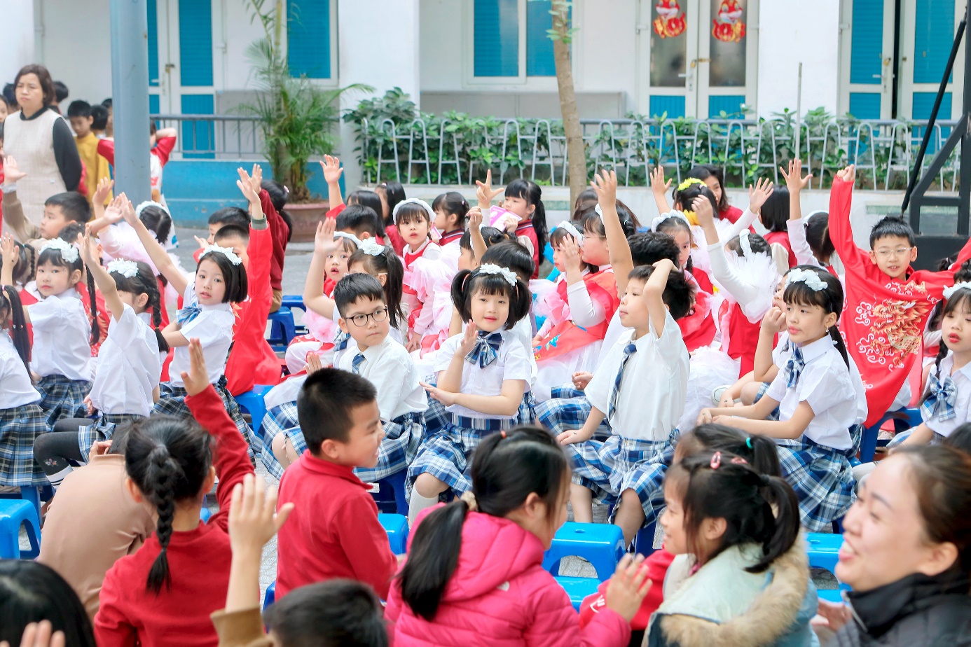 A group of children in a circle raising their hands

Description automatically generated