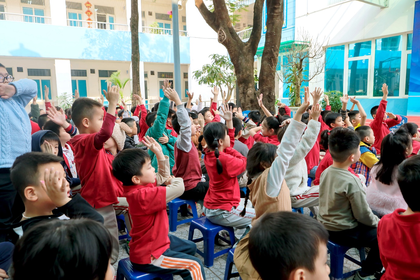 A group of children raising their hands

Description automatically generated