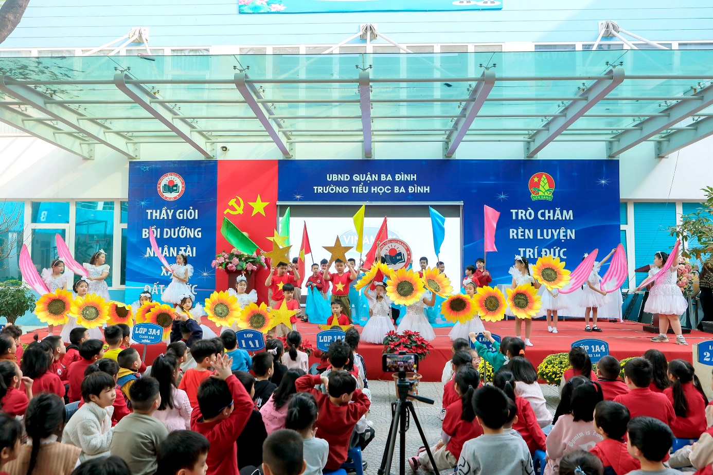 A group of children sitting on a stage

Description automatically generated