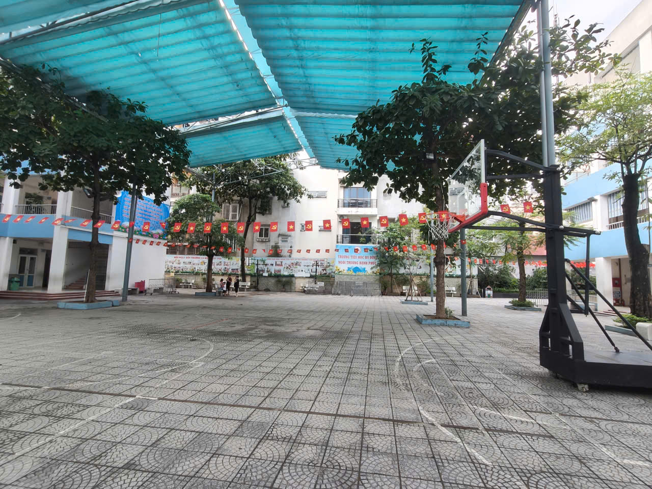 A basketball court with trees and a blue roof

AI-generated content may be incorrect.