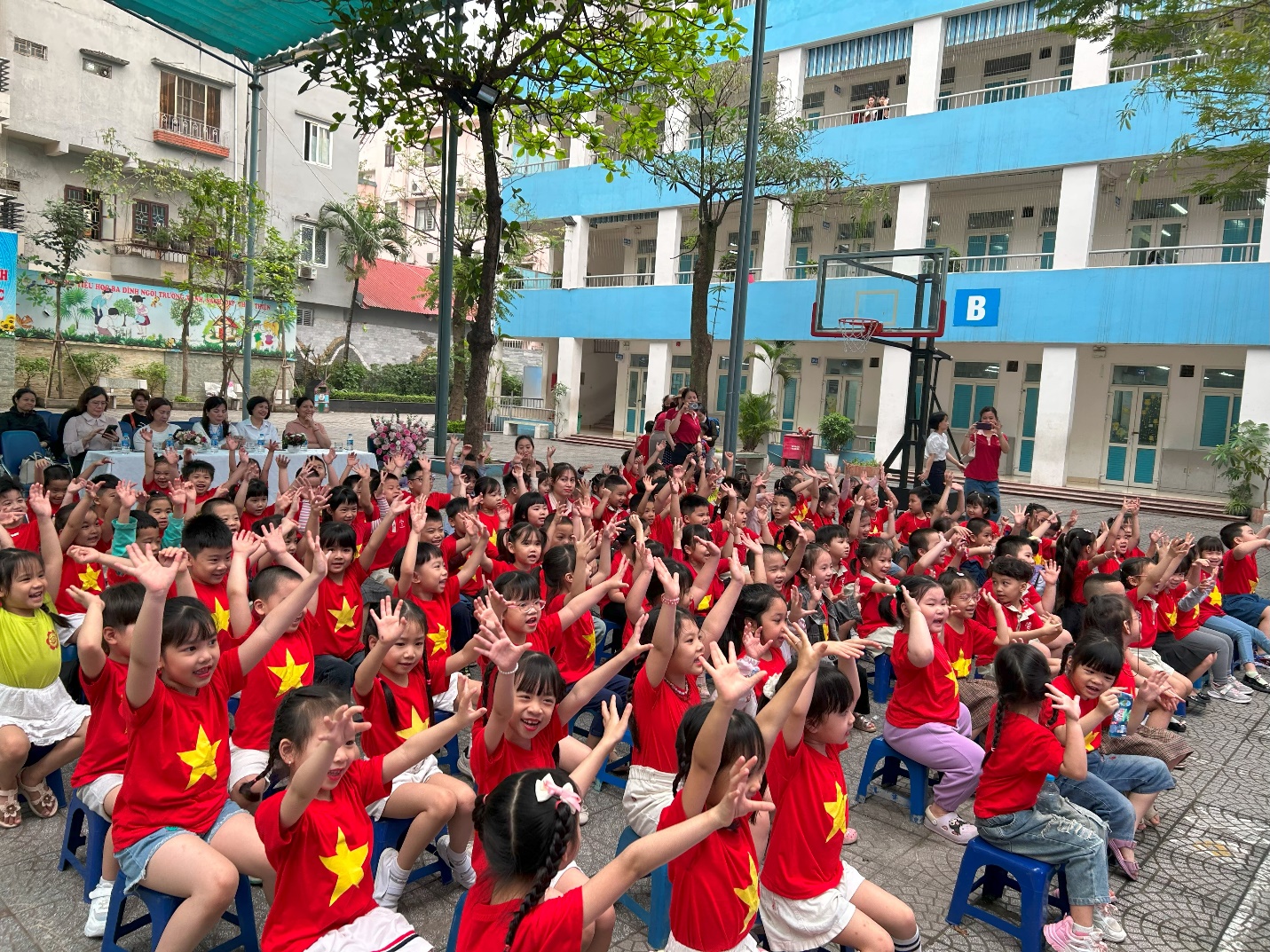 A group of children sitting on blue chairs with their hands up

AI-generated content may be incorrect.