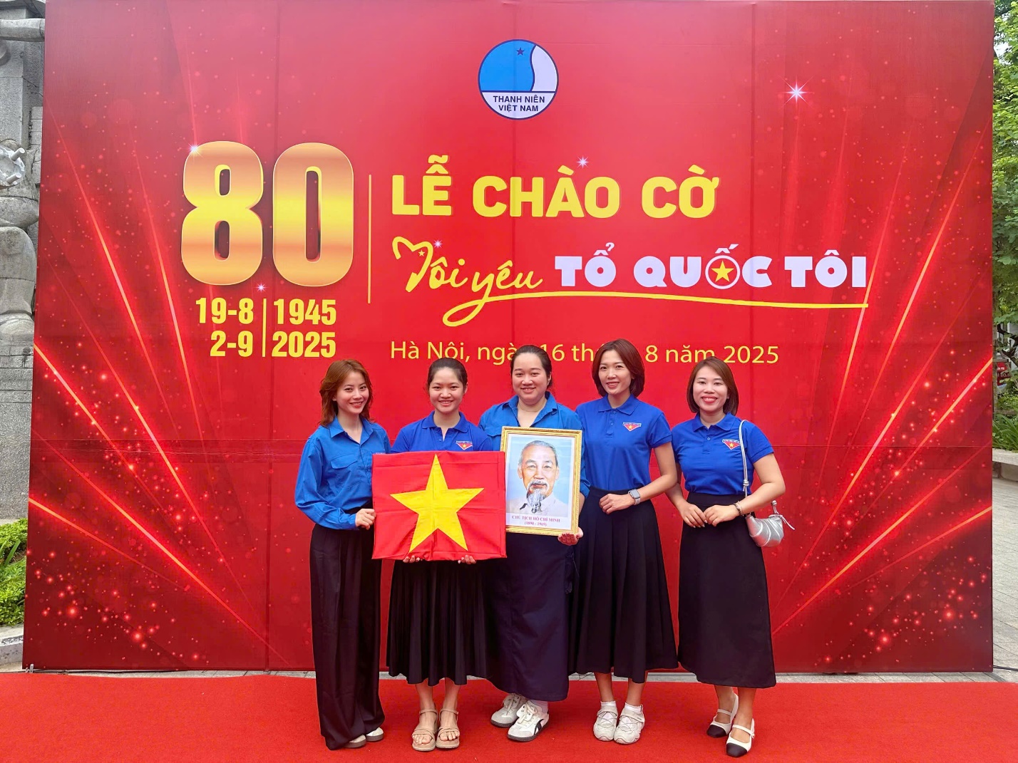 A group of women holding a flag and a picture

AI-generated content may be incorrect.