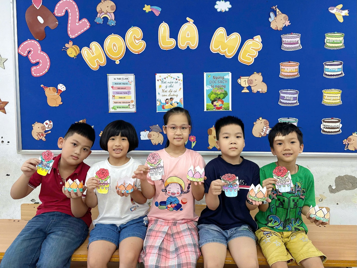 A group of children sitting on a bench holding up paper cupcakes

AI-generated content may be incorrect.