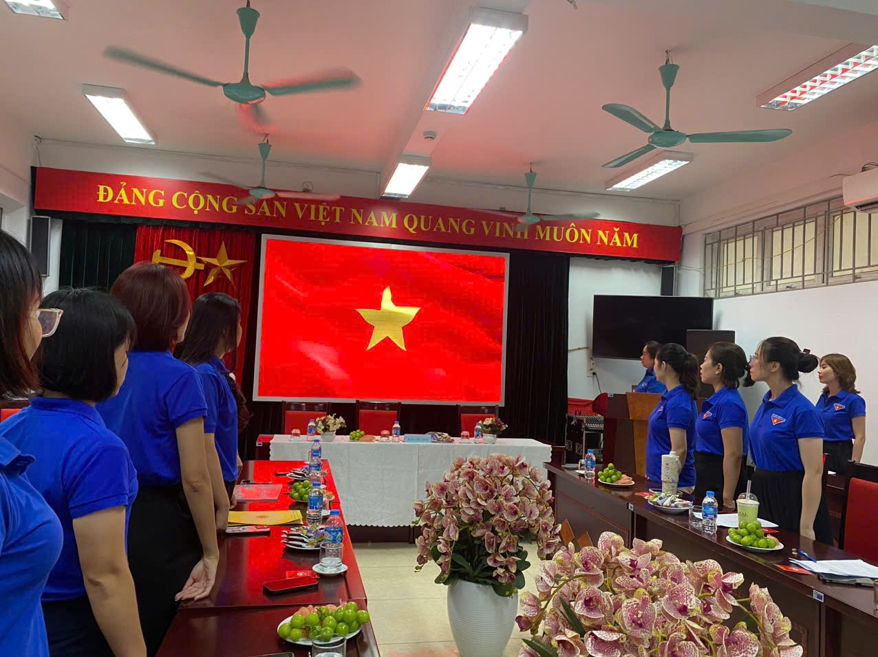 A group of people in a room with a red flag

Description automatically generated