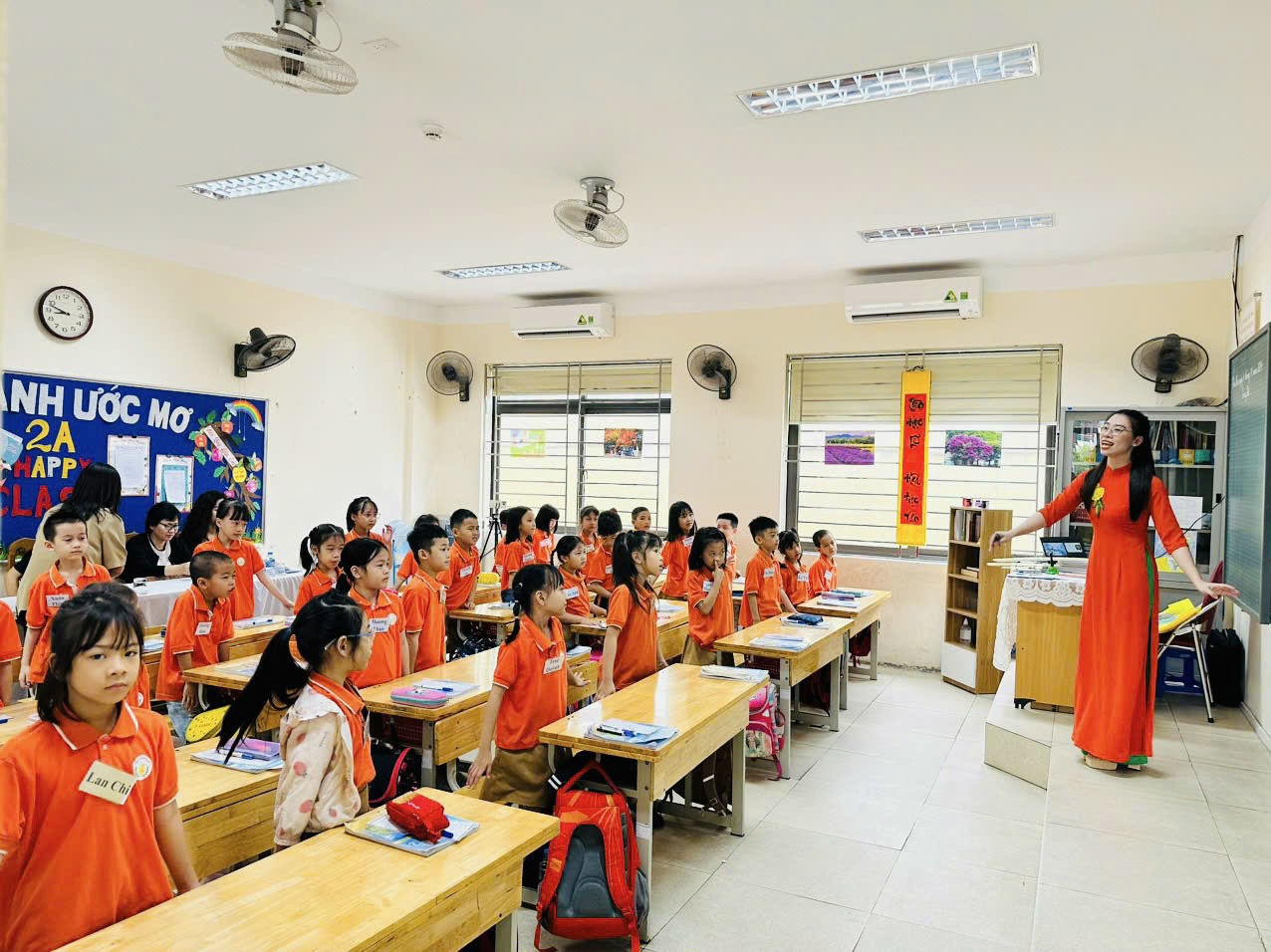 A person standing in front of a group of children in a classroom

Description automatically generated