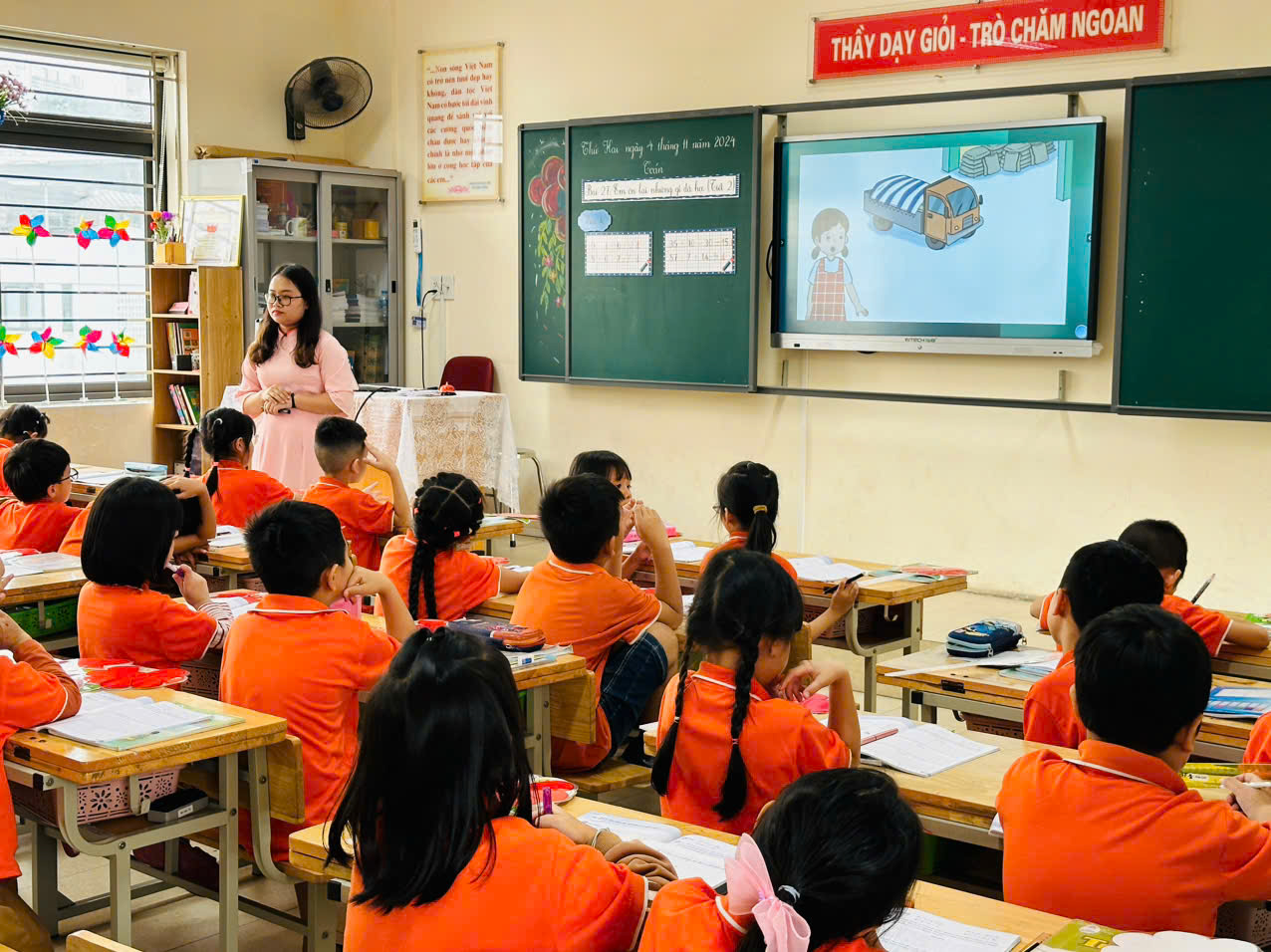 A person standing in front of a classroom with a group of children

Description automatically generated