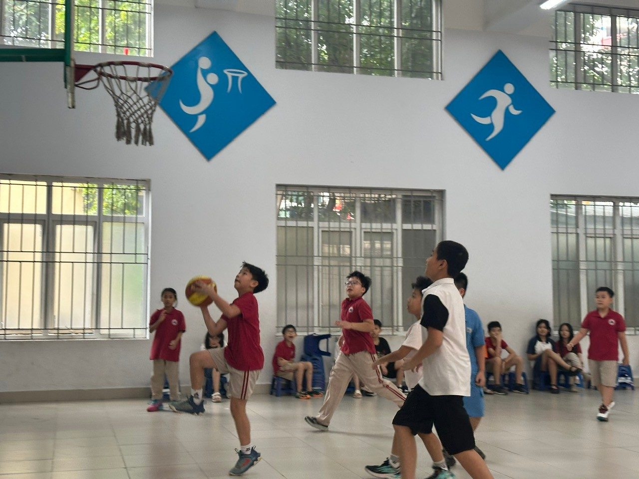 A group of kids playing basketball in a gym

Description automatically generated