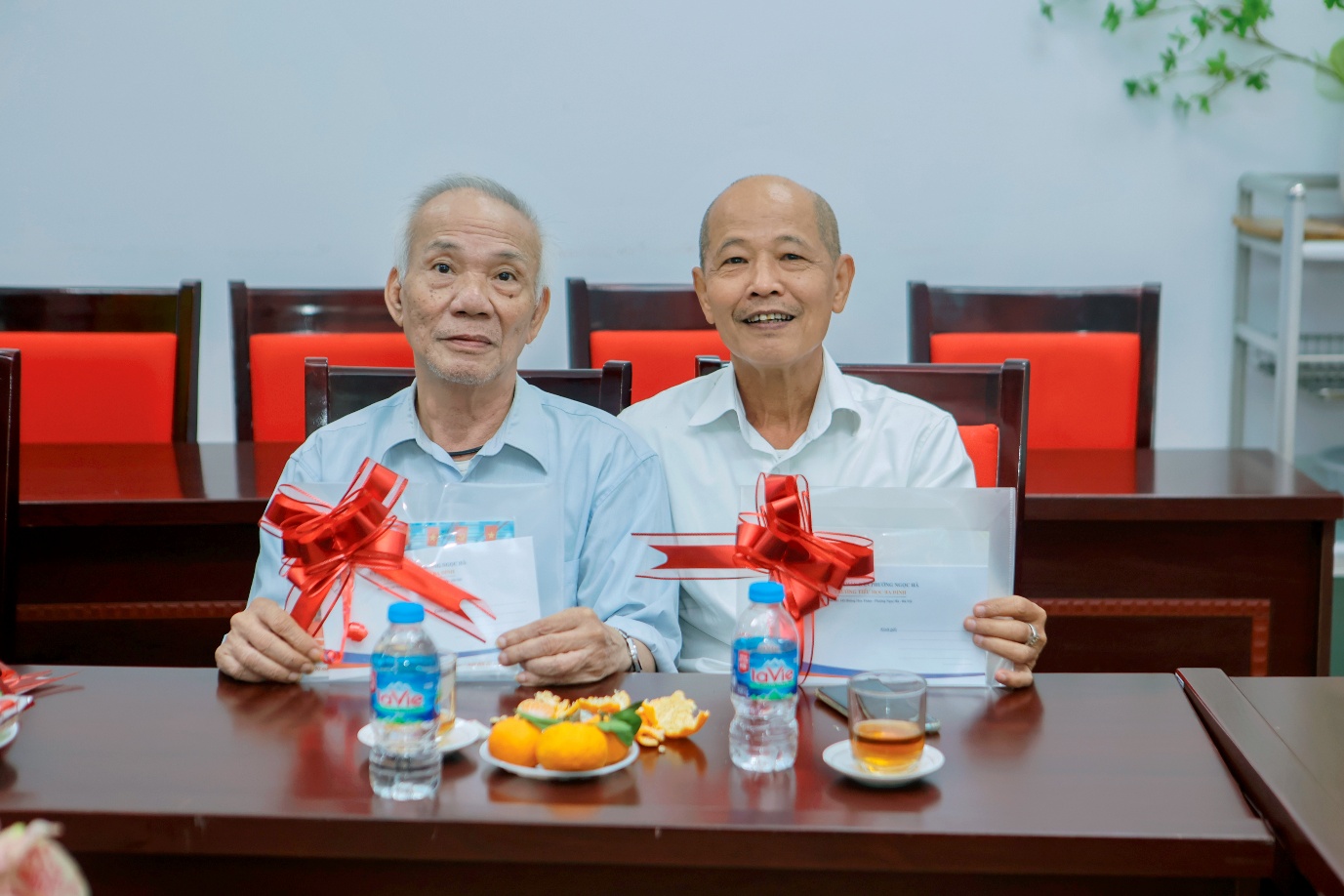 Two men sitting at a table with a gift

AI-generated content may be incorrect.