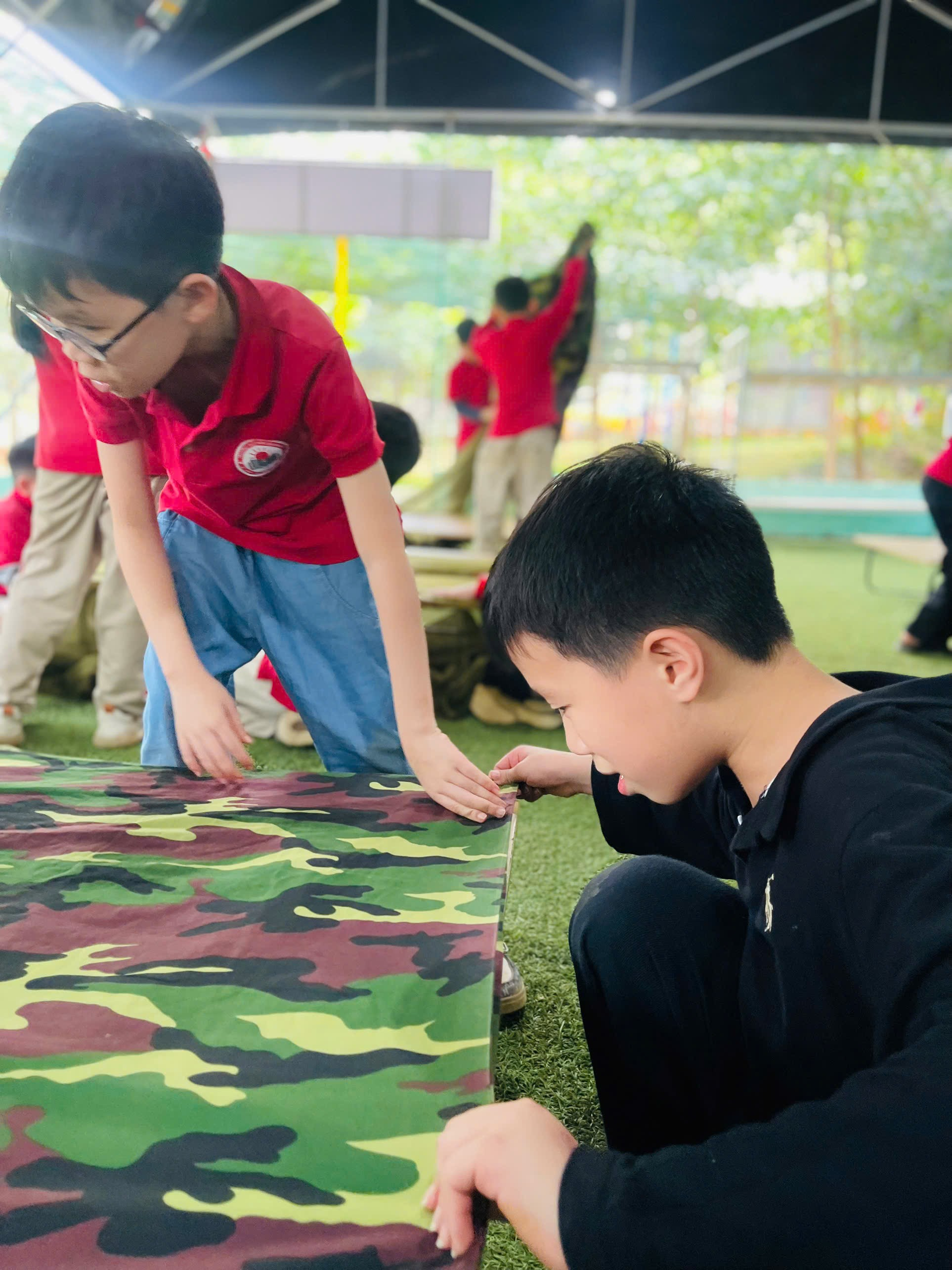 A group of boys looking at a camouflage fabric

AI-generated content may be incorrect.