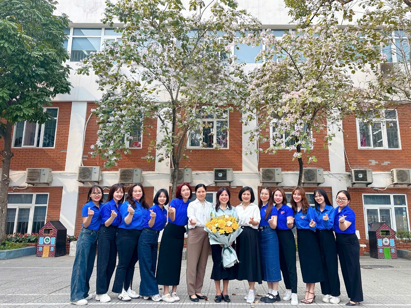 A group of women in blue shirts and blue shirts standing in front of a building

AI-generated content may be incorrect.