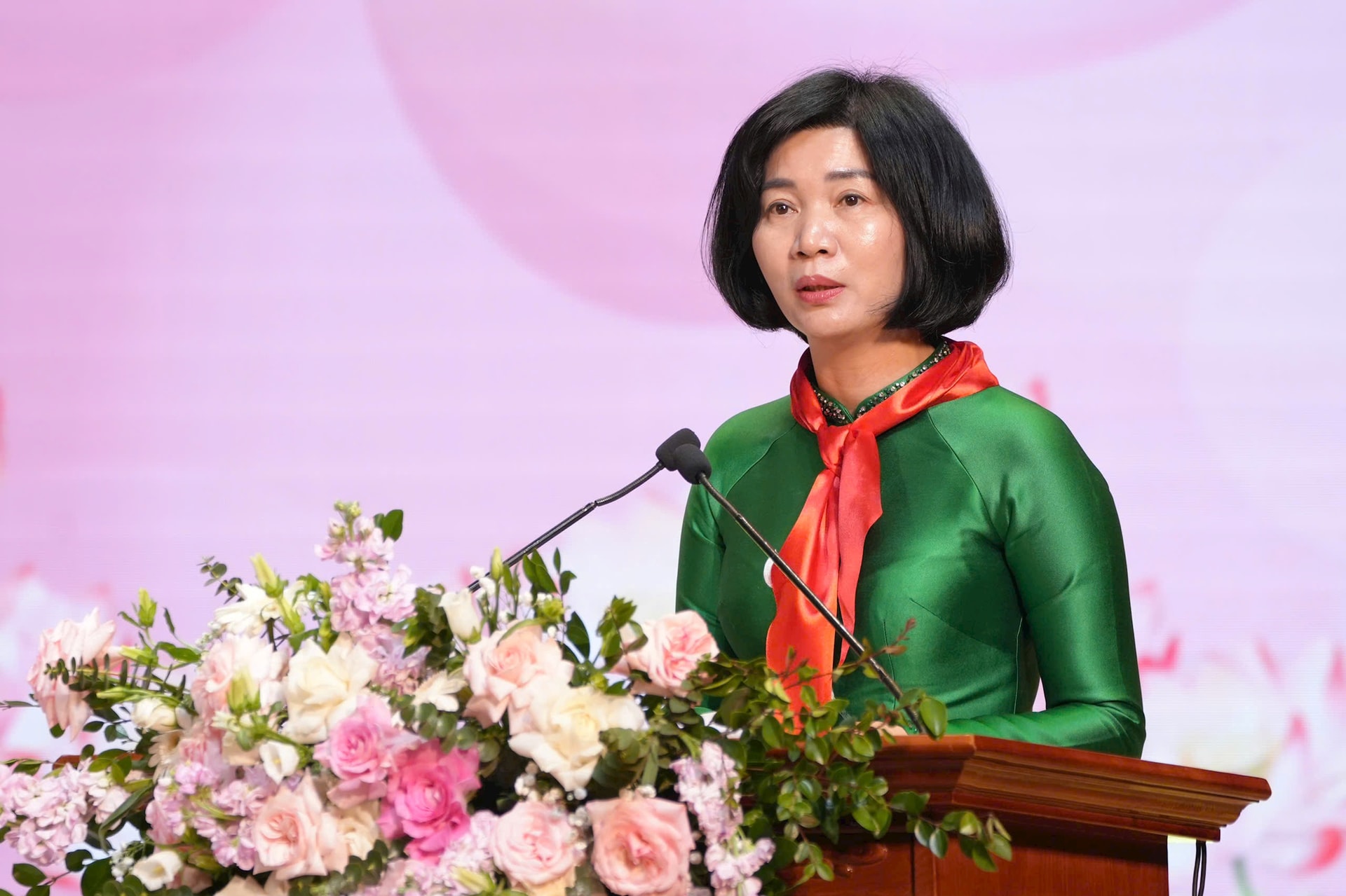 A person standing at a podium with a microphone and flowers

AI-generated content may be incorrect.