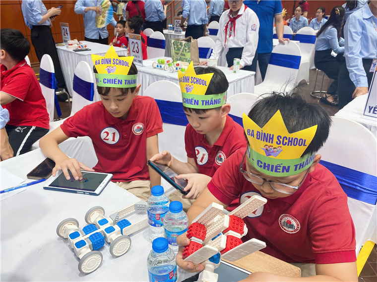 A group of boys wearing paper crowns and looking at a device

Description automatically generated